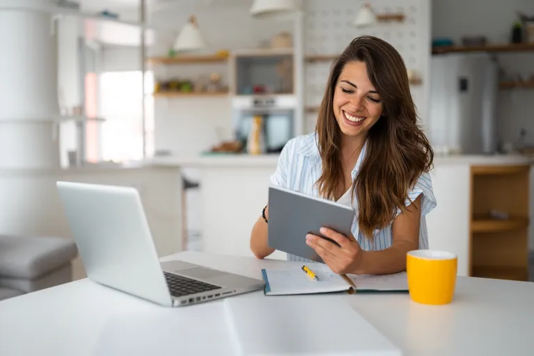 Mulher trabalhando com tablet e notebook enquanto empreende em casa