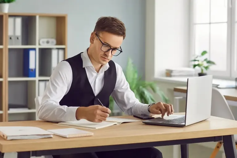 Profissional analisando dados e preenchendo balanço do negócio no notebook
