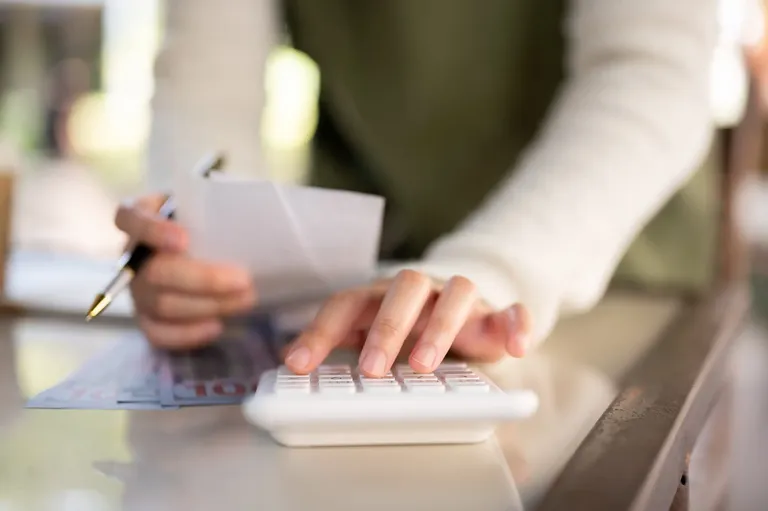 Pessoa calculando despesas com notas e calculadora para melhorar a organização financeira