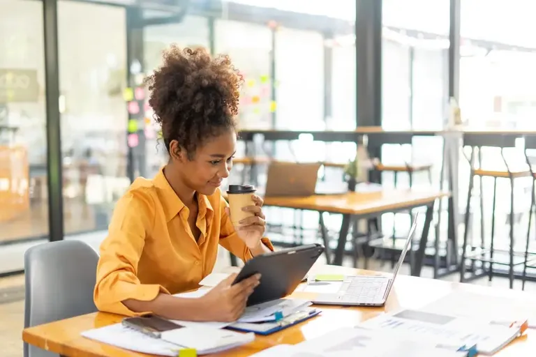 Empreendedora analisando dados em tablet e laptop durante pesquisa de mercado