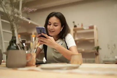 Empreendedora usando o celular para organizar o controle financeiro da sua loja