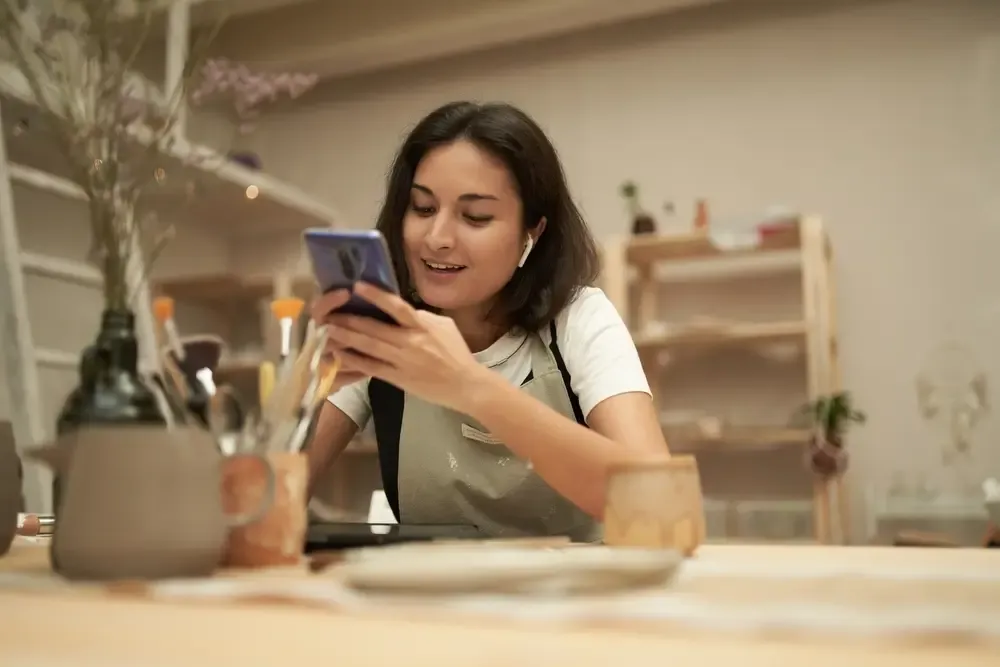 Empreendedora usando o celular para organizar o controle financeiro da sua loja