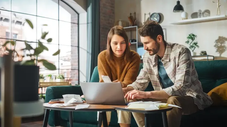 Casal analisando despesas e organizando o controle financeiro no notebook