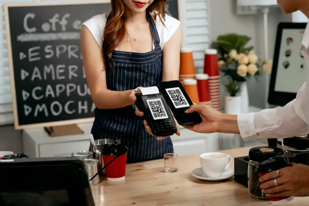 Cliente realizando pagamento por QR Code no ponto de venda de uma cafeteria