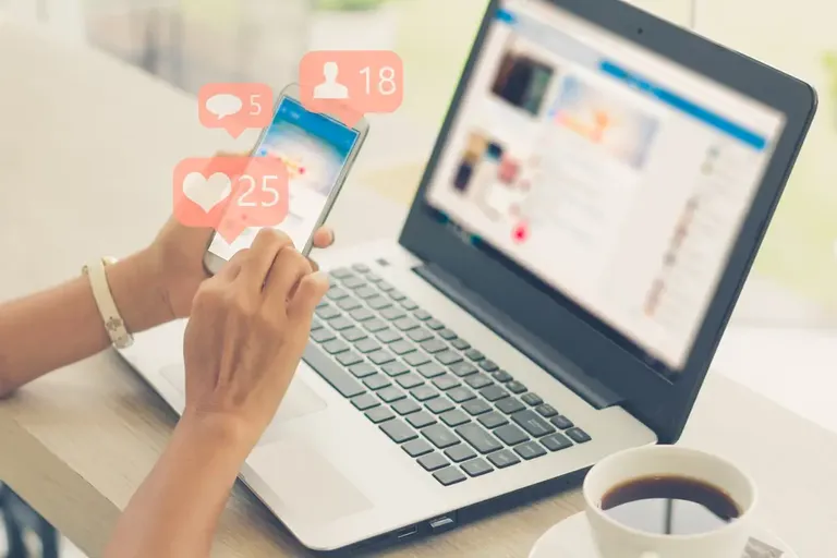 Pessoa usando celular e notebook para divulgar produtos nas redes sociais e vender mais