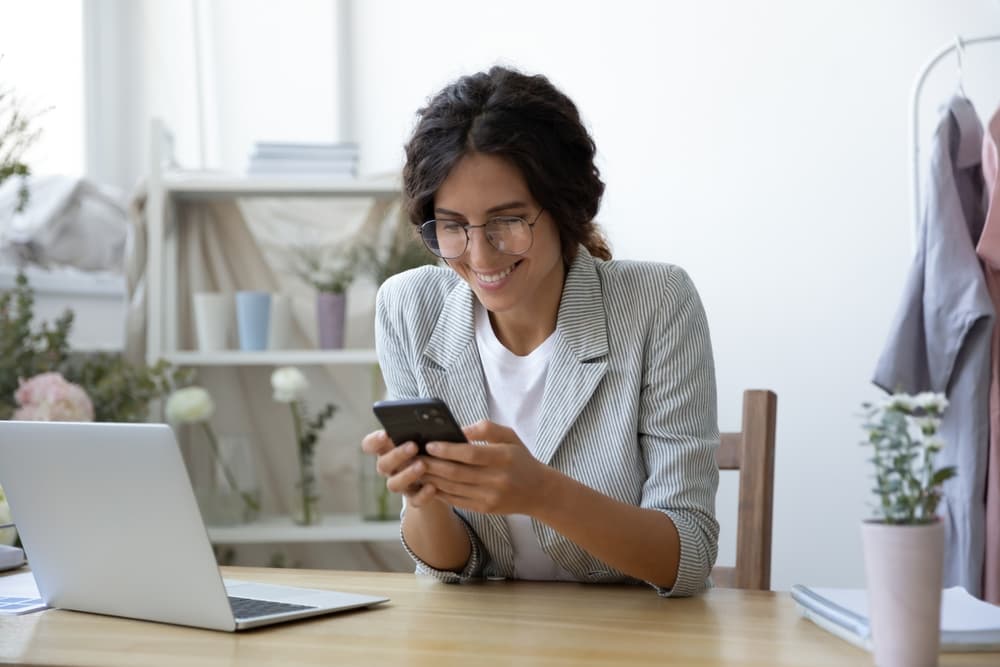 Mulher organizando tarefas no celular enquanto tenta profissionalizar seu negócio