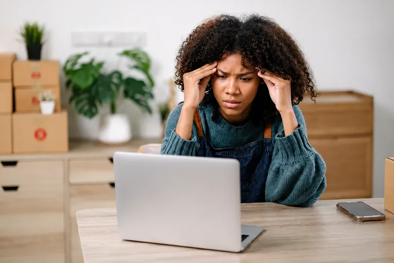 Empreendedora estressada em frente ao laptop por fazer tudo sozinho no negócio