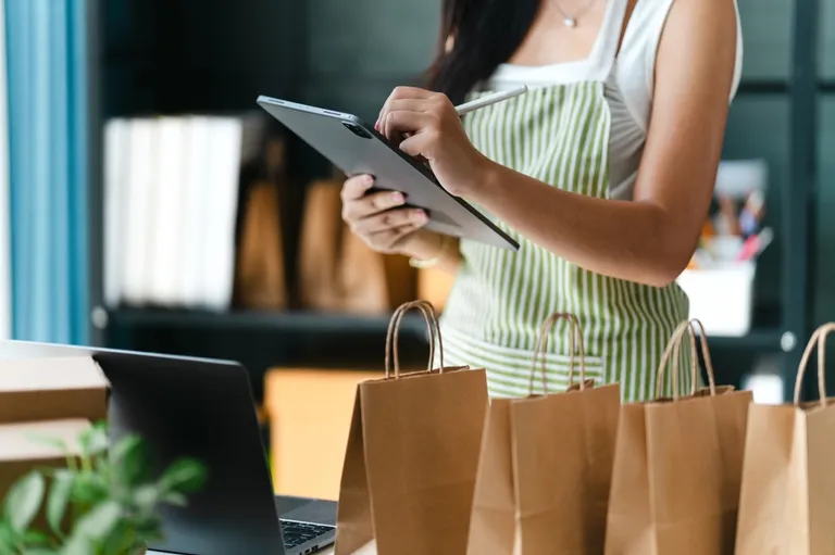 Empreendedora usando tablet para organizar pedidos de clientes em pequena loja