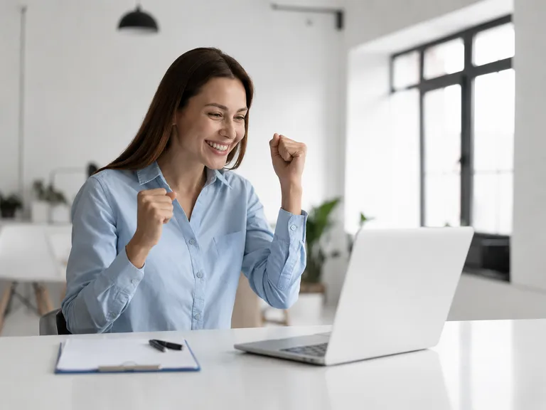 Empreendedora sorrindo na frente do computador ao organizar a gestão da sua pequena empresa