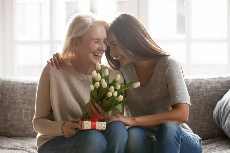 Momento de carinho entre mãe e filha com flores e presente de Dia das Mães