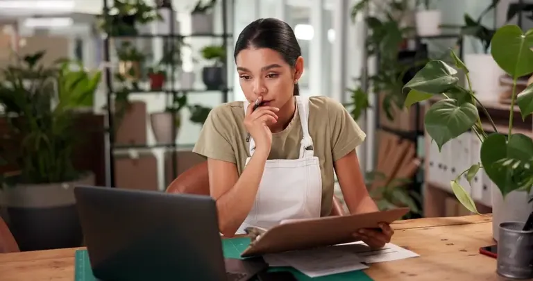 Empreendedora analisando dados no notebook enquanto atualiza cadastro de clientes