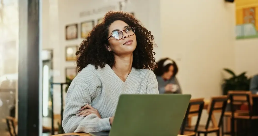 Empreendedora pensando em novas oportunidades enquanto usa o laptop