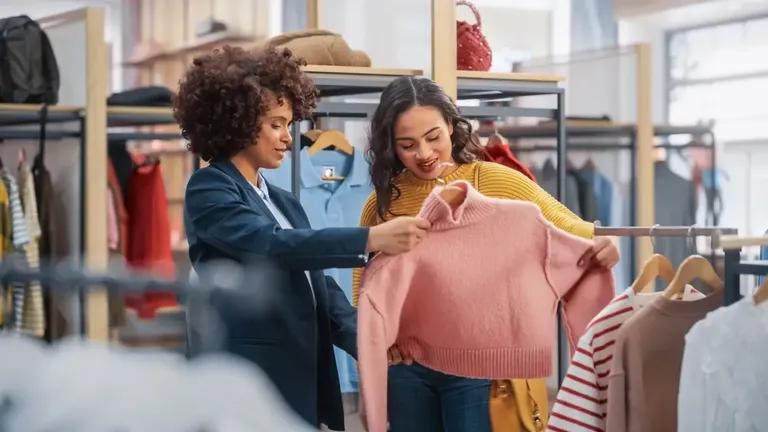 Cliente avaliando uma peça de roupa com ajuda da vendedora durante a experiência de compra