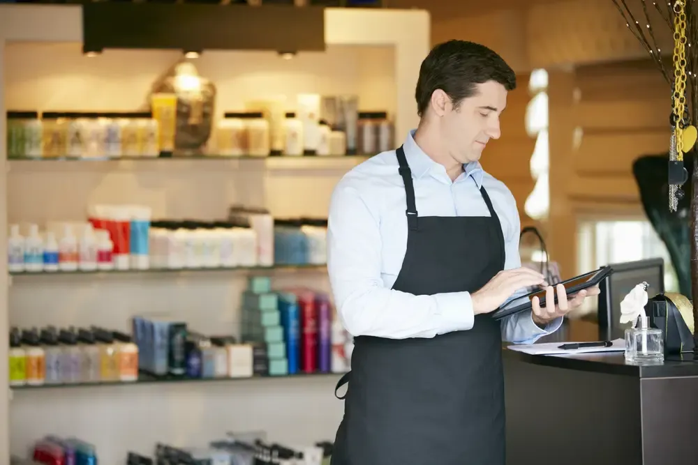 Comerciante usando tablet no balcão da loja para acessar ferramentas de gestão