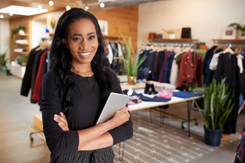 Empreendedora de moda analisando preços e estratégias de precificação com tablet na loja