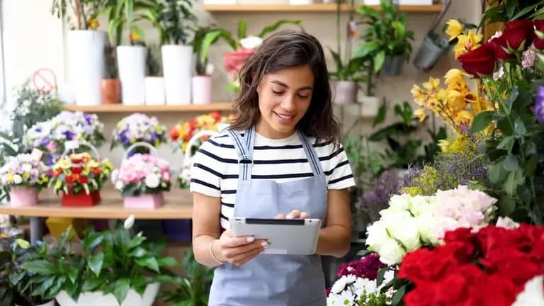 Florista registrando productos en una tablet mientras organiza arreglos florales