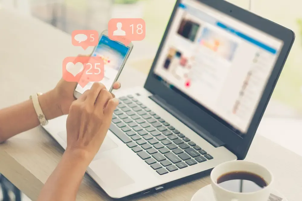 Pessoa usando celular e notebook para divulgar produtos nas redes sociais e vender mais